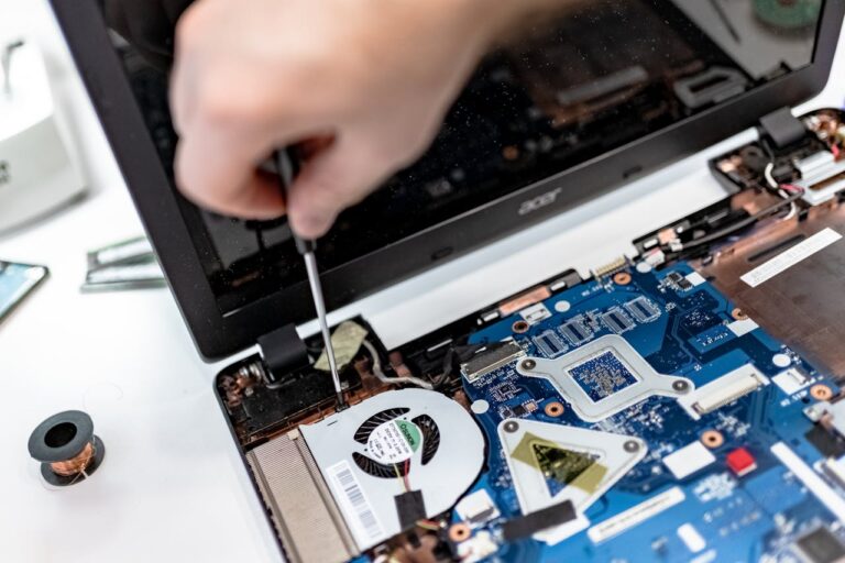 technician has laptop open to expose motherboard for repairs